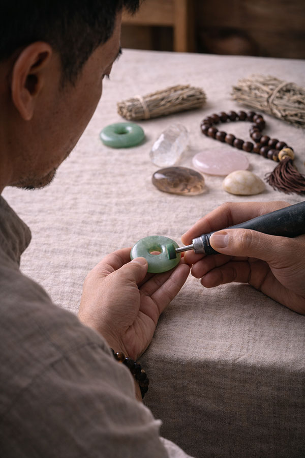 Asian craftsman carefully polishing a jade pendant by hand as part of the Eastern Story making process