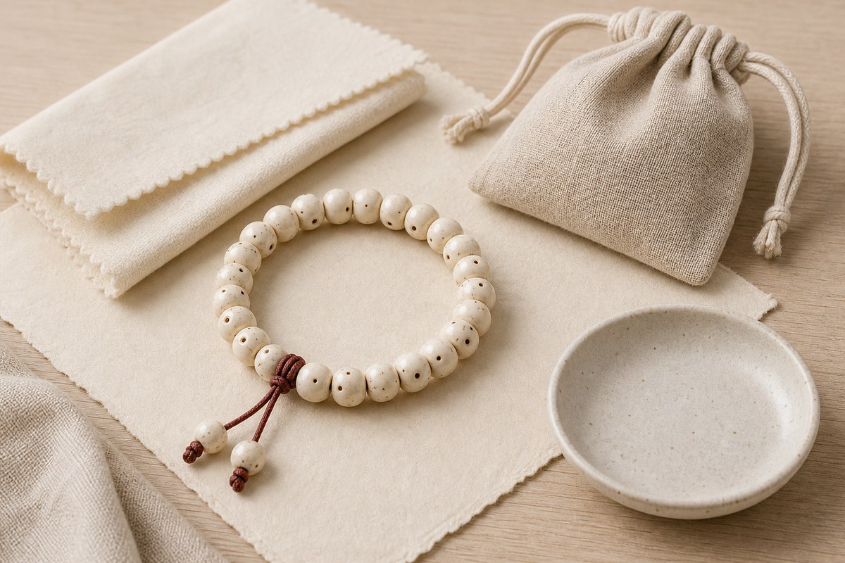 White bodhi bracelet beside a dry cloth, linen pouch, and ceramic dish