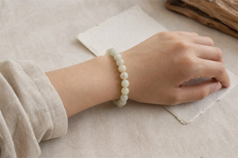 Person wearing a pale Hetian jade bracelet with a simple linen outfit
