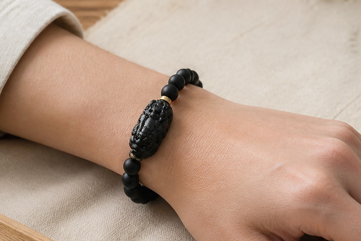 Black Pixiu bracelet on a wrist with the carved charm facing outward