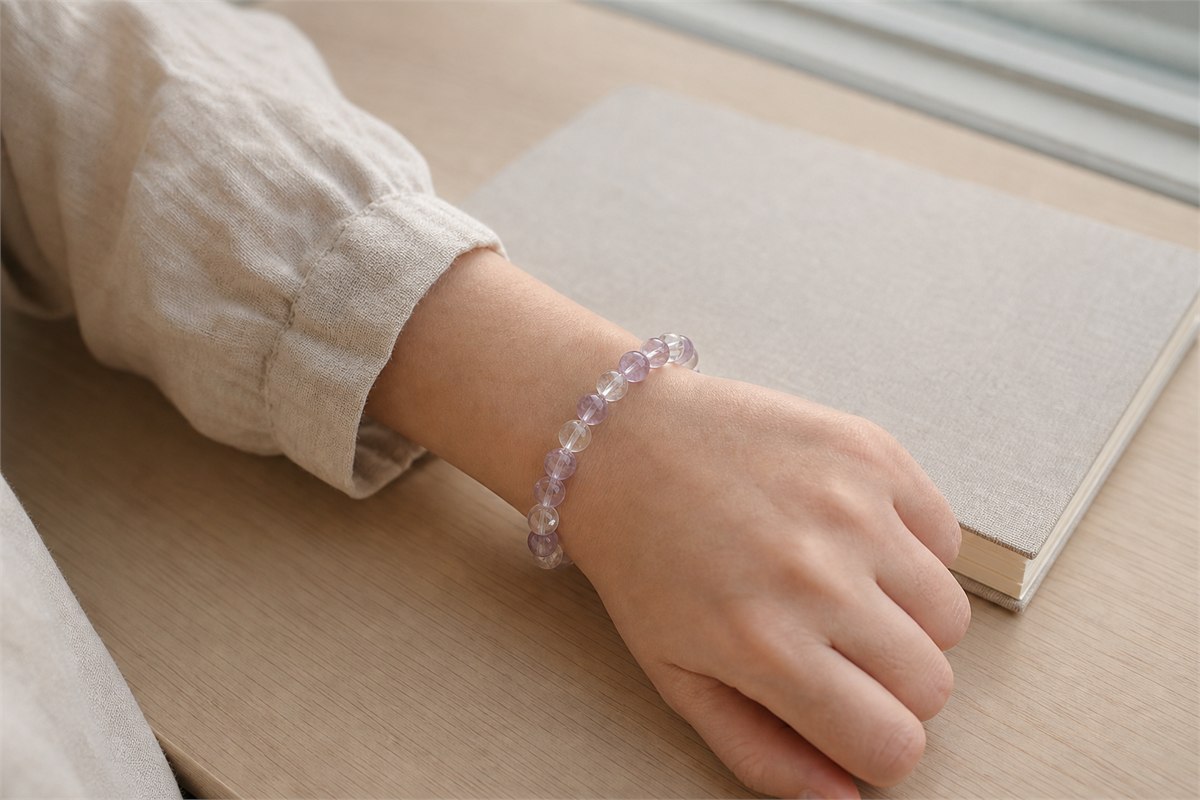 A moderate 8 mm pale amethyst and clear quartz bracelet worn at a bright work desk