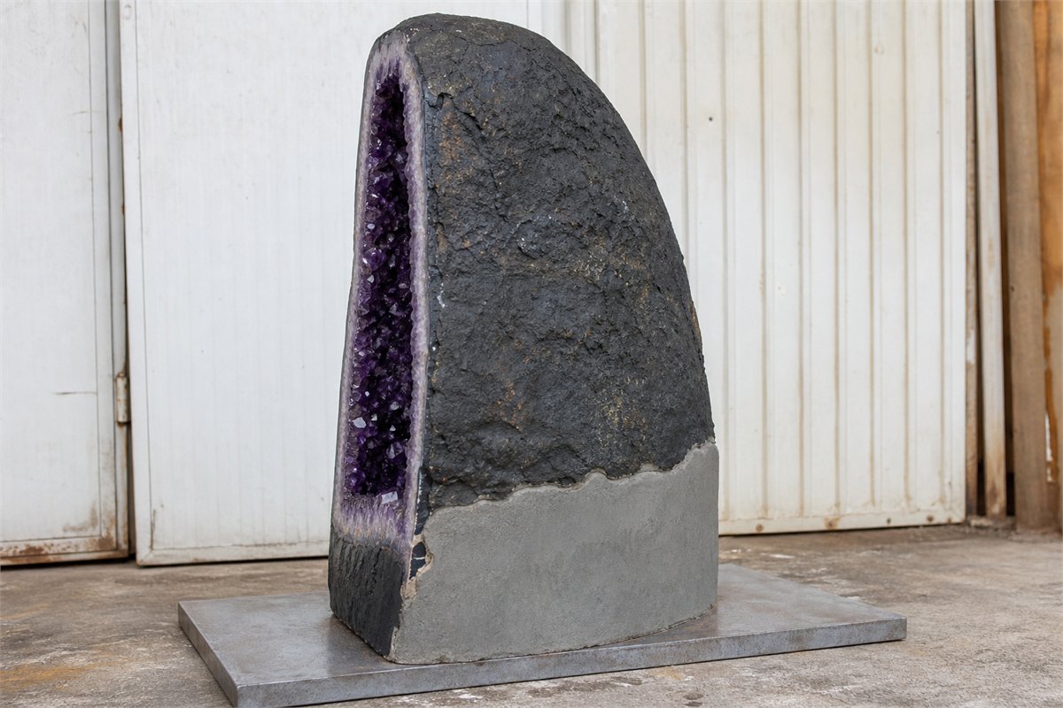 Rear view of an amethyst cathedral with visible concrete support backing and broad base