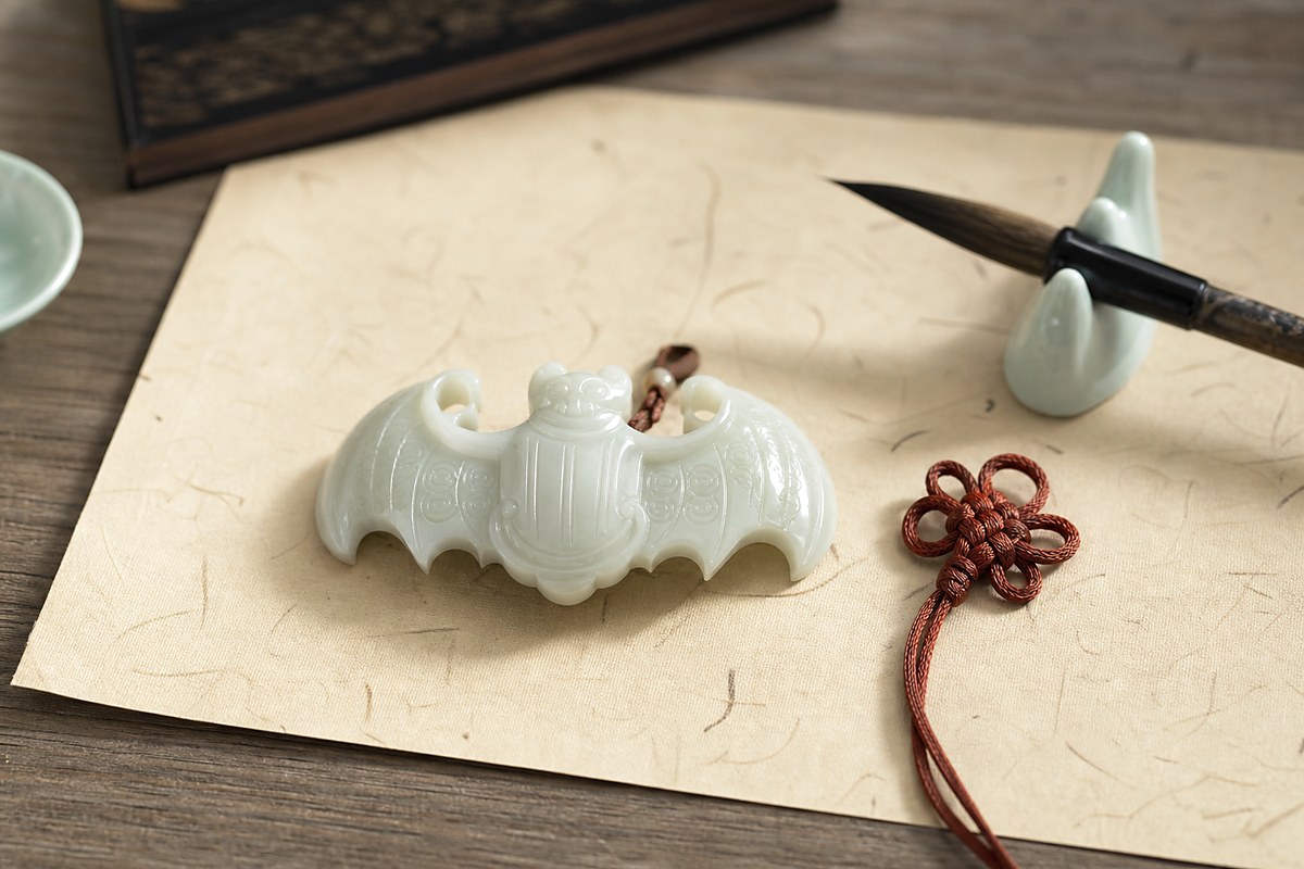 White jade bat motif on parchment with brush and cinnabar cord for Fu blessing symbolism