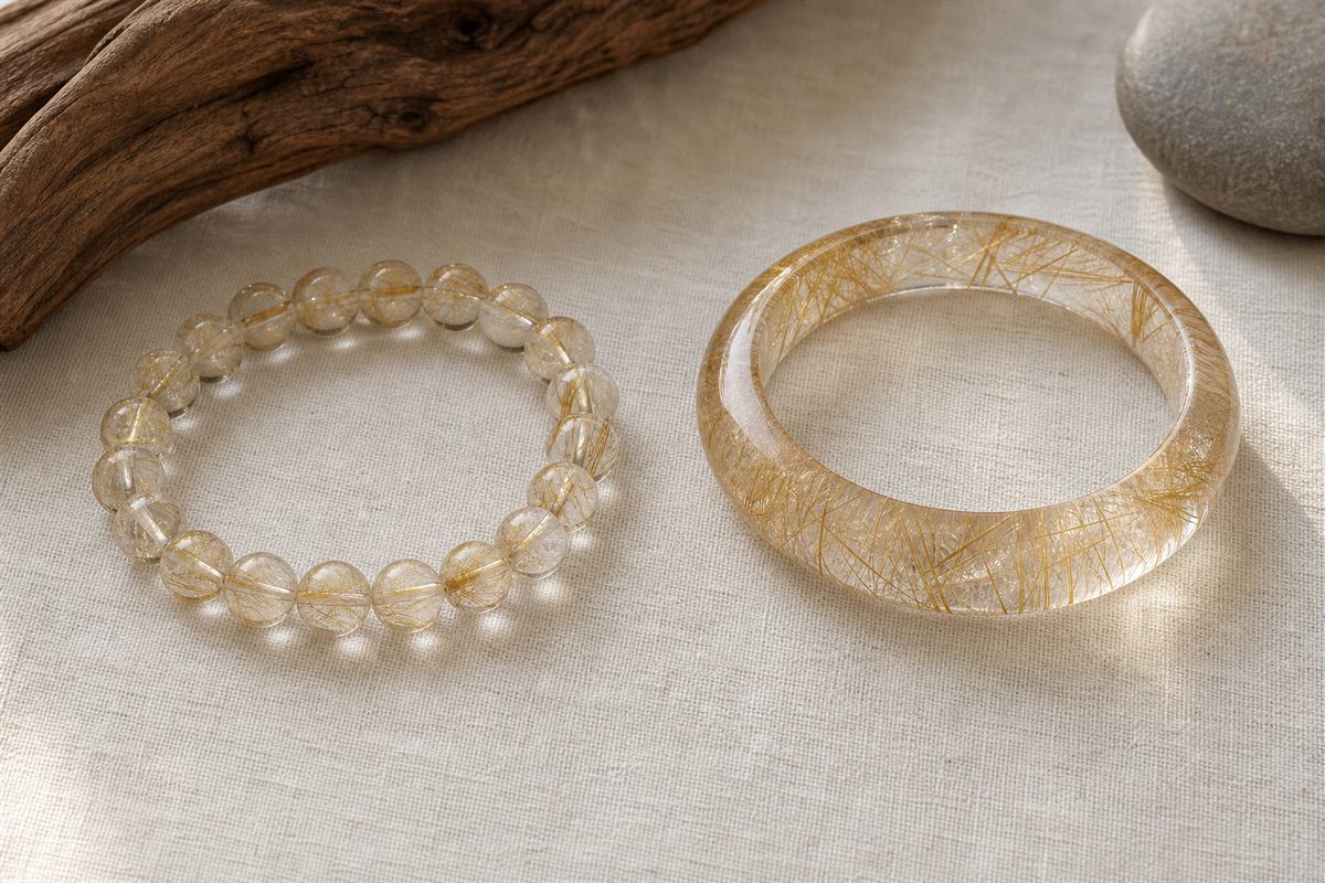 Flexible rutilated quartz bead bracelet beside a one-piece polished rutilated quartz hard bangle