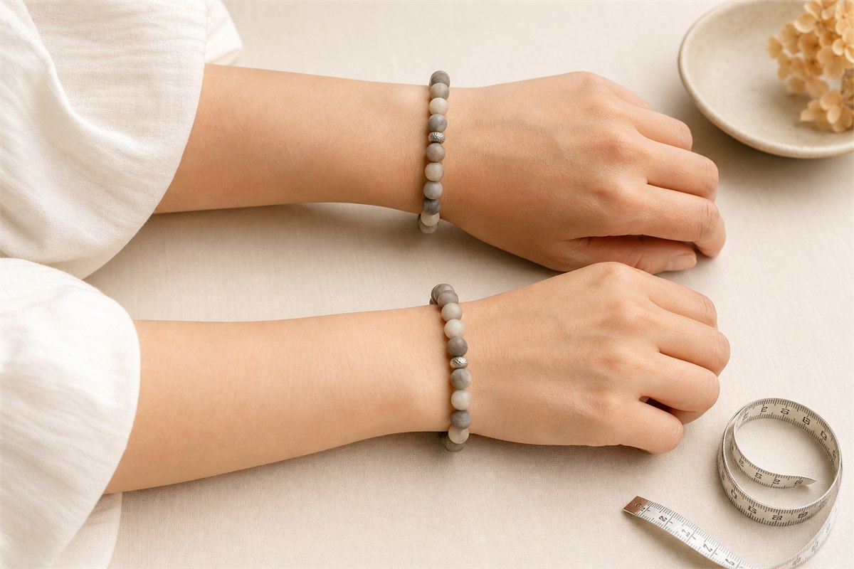 Two wrists wearing similar matte stone bracelets with different comfortable fits