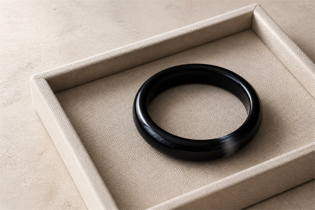 Black agate bangle resting safely in a padded tray away from a hard stone edge