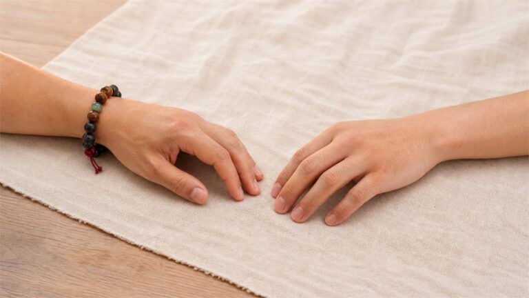 Two relaxed adult hands with a mixed wood stone and cord bracelet worn on one wrist