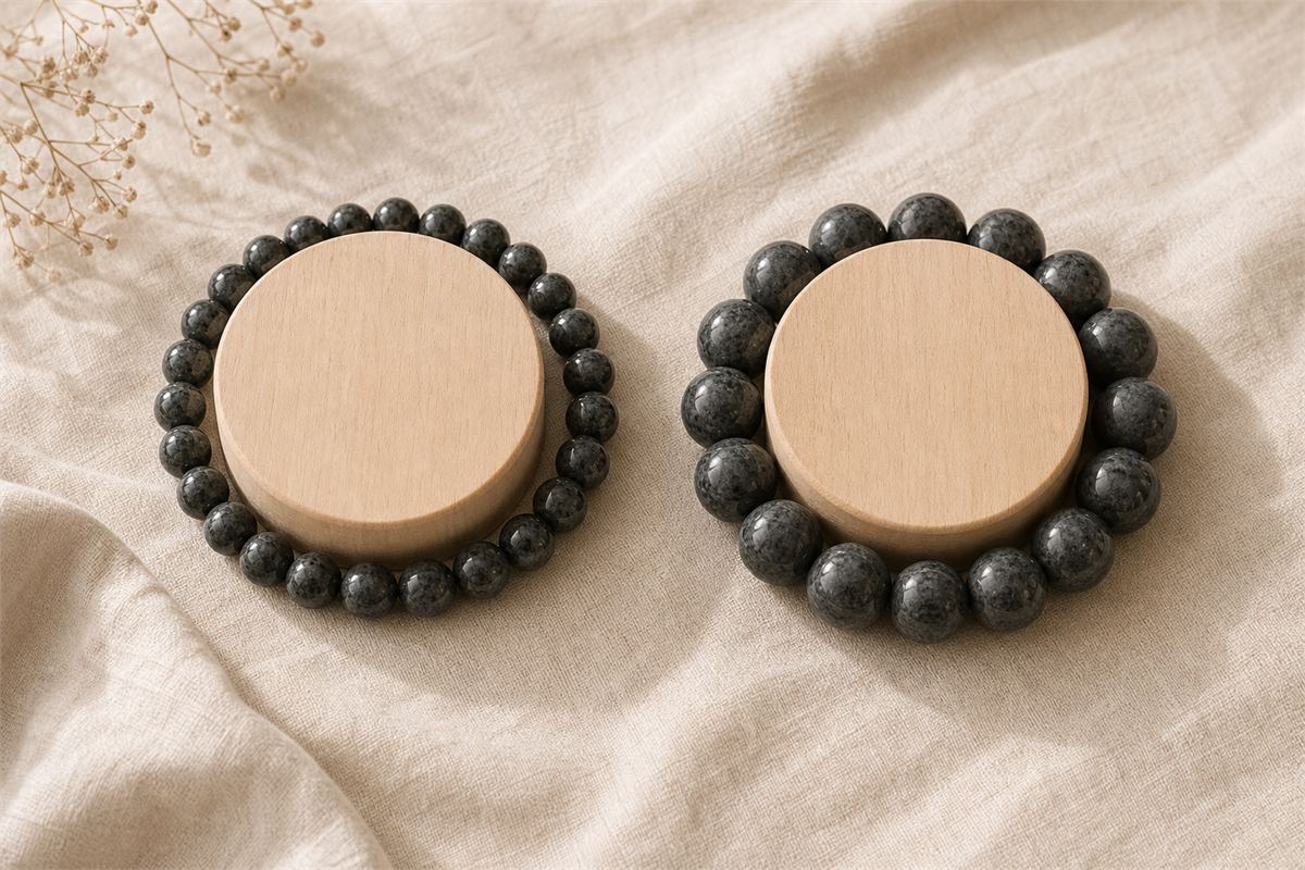 Small and large dark bead bracelets arranged around identical wooden sizing forms