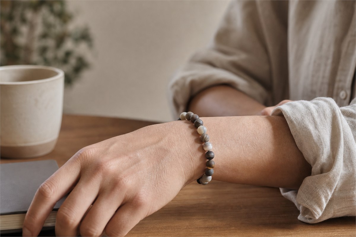 Relaxed wrist wearing a well-fitting matte stone bead bracelet at a desk