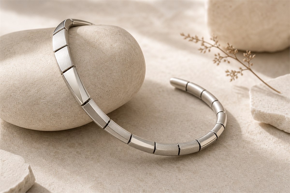 Abstract silver bracelet with articulated tapered segments curving around a pale stone form