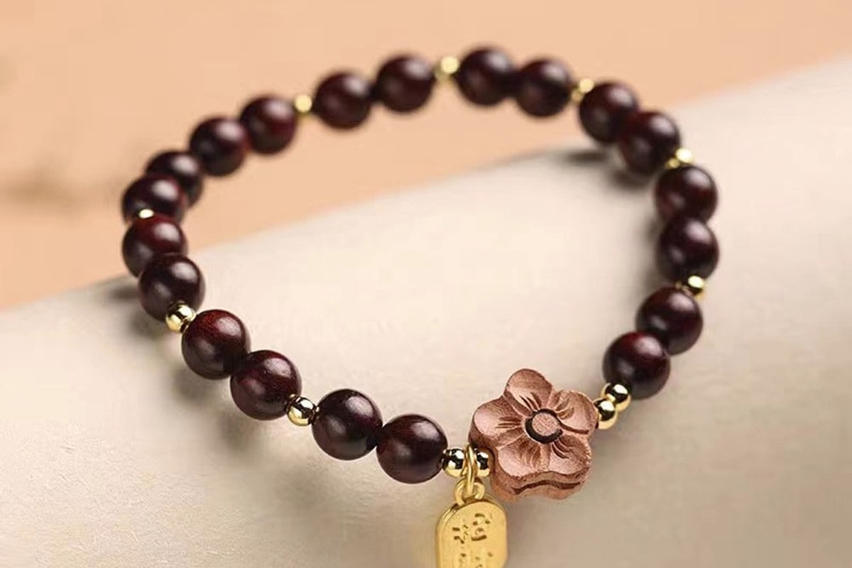Dark wood bracelet resting on warm fabric with a soft polished surface