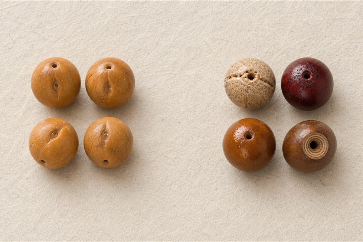 Natural Fengyan Bodhi beads beside examples with concave eyes, dead-red dye, oily shine, and spiral drilling marks