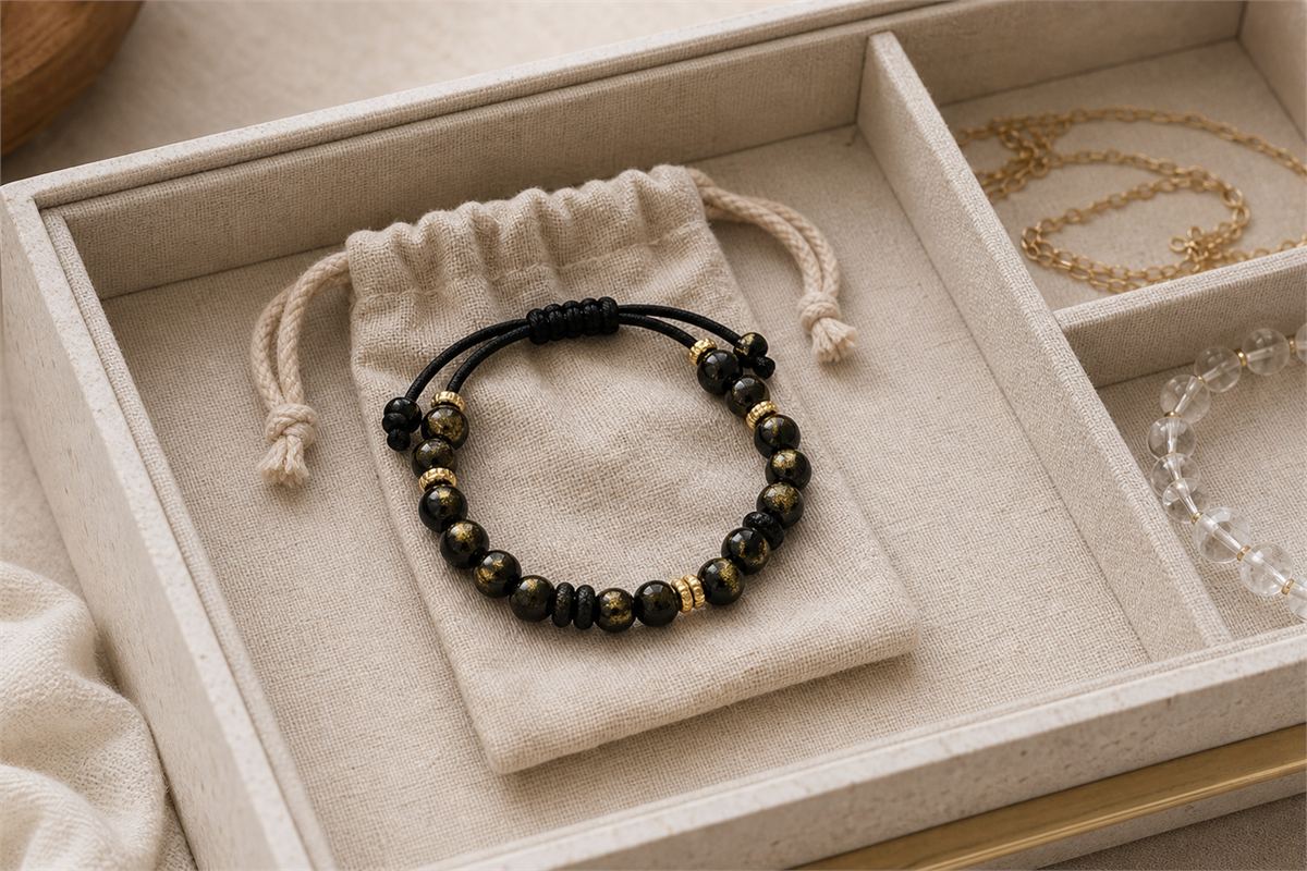 Gold sheen obsidian bracelet stored in a soft pouch separate from quartz jewelry and metal chain
