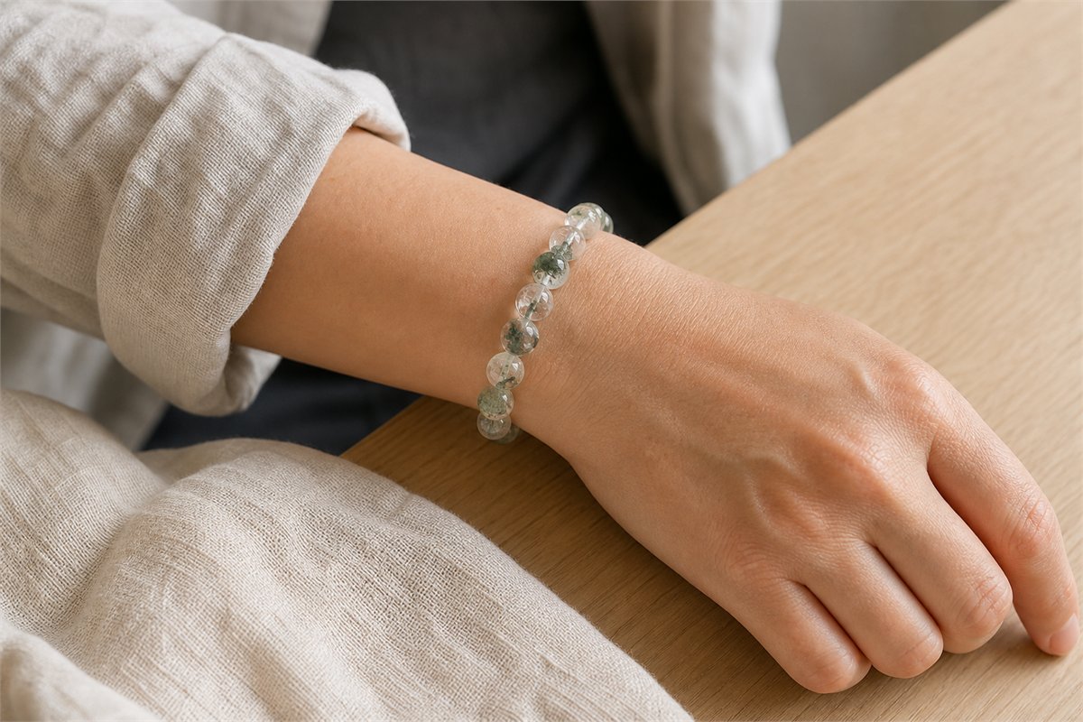 Adult wrist wearing varied clear quartz beads with natural olive-green chlorite inclusions