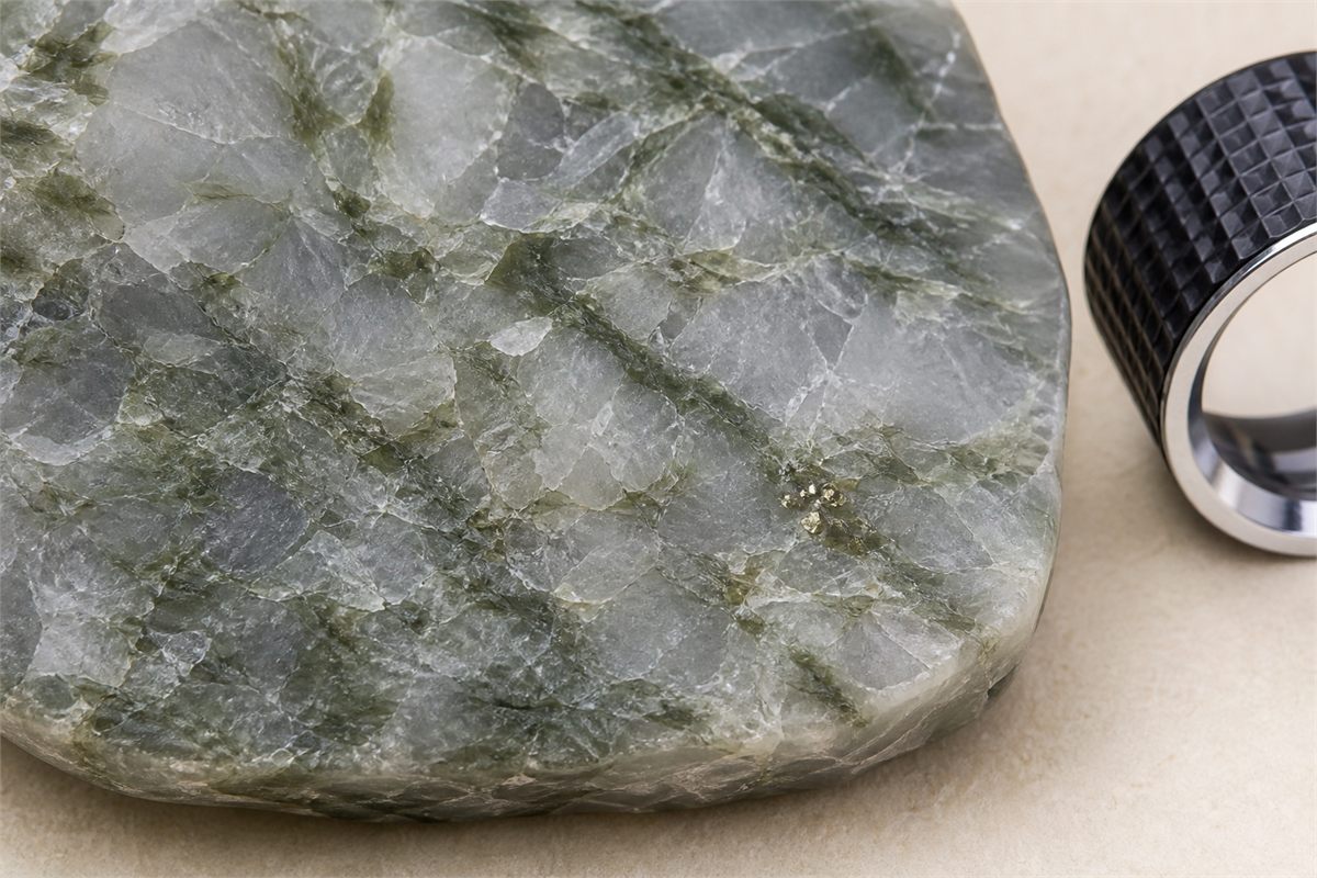 Macro view of green quartzite grains with mica-like wisps and a few localized brassy mineral points