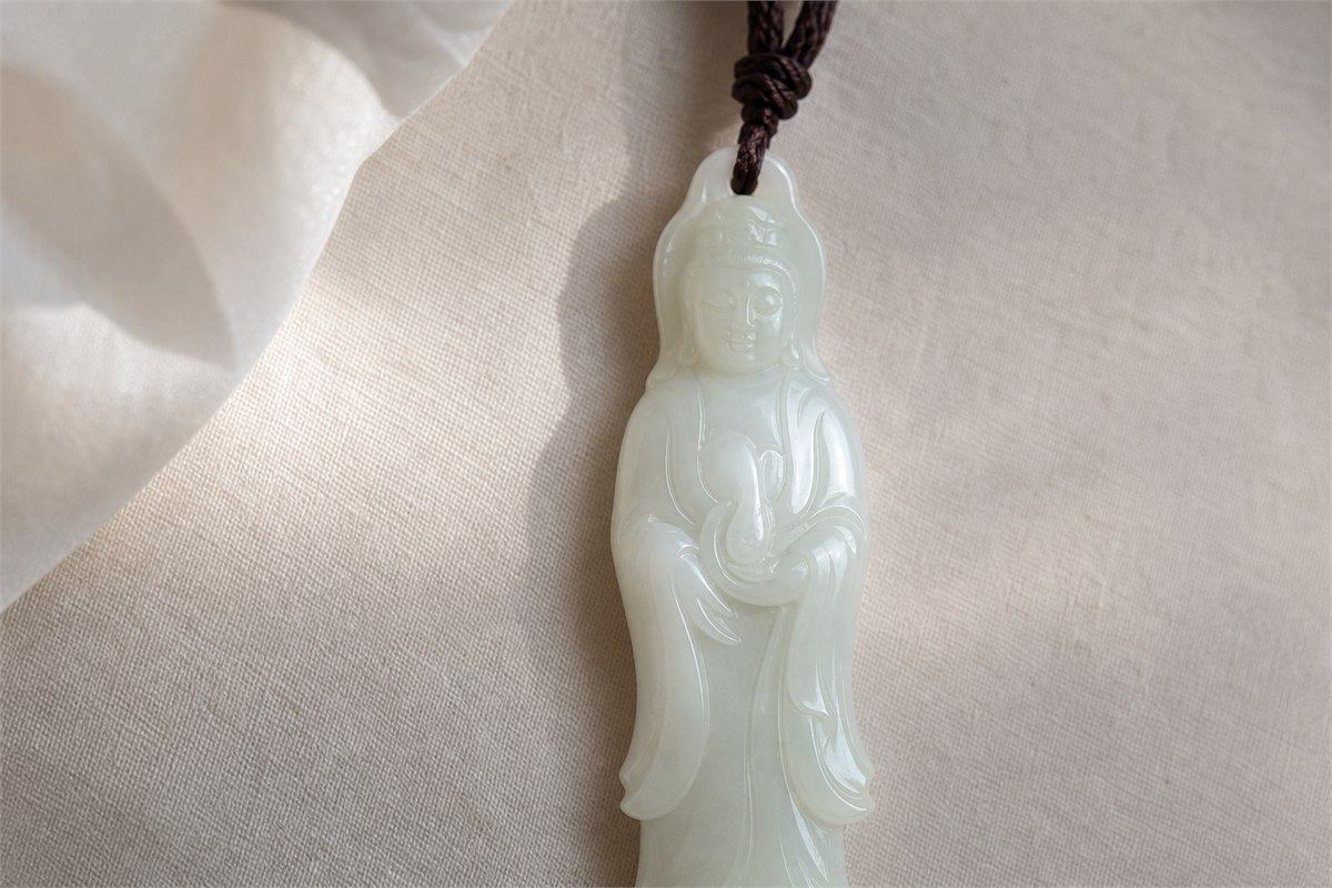 Serene white nephrite Guanyin pendant with flowing robes in soft window light