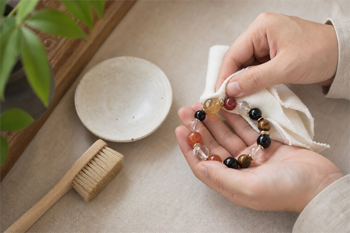 Hands gently wiping a mixed-material bracelet with a soft lint-free cloth