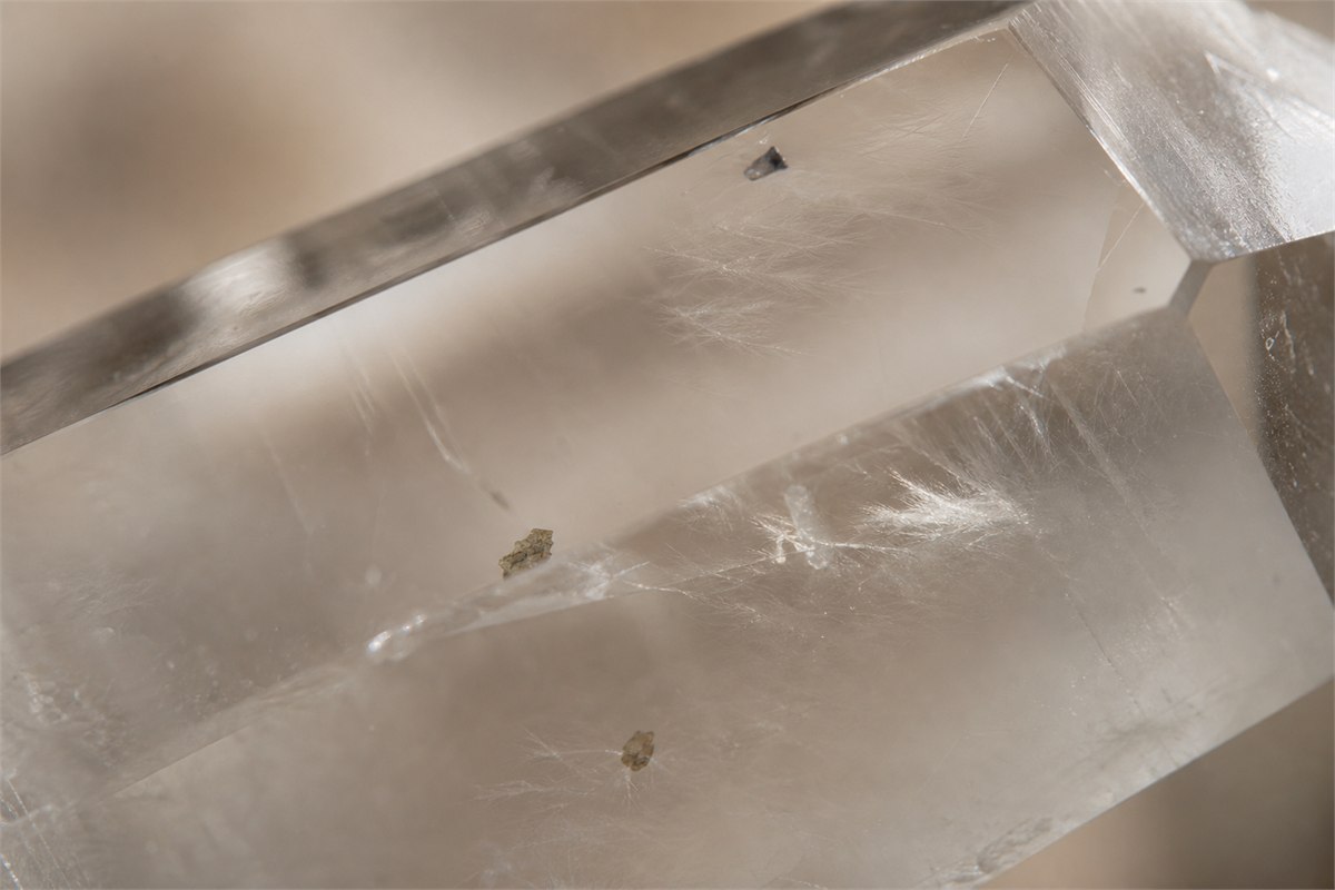 Macro view through natural quartz showing irregular veils, healed fractures, faint color zoning, and tiny mineral inclusions