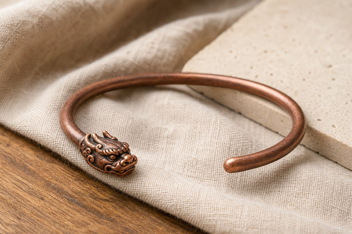 Red copper open cuff with one sculpted Pixiu head terminal and one plain rounded terminal