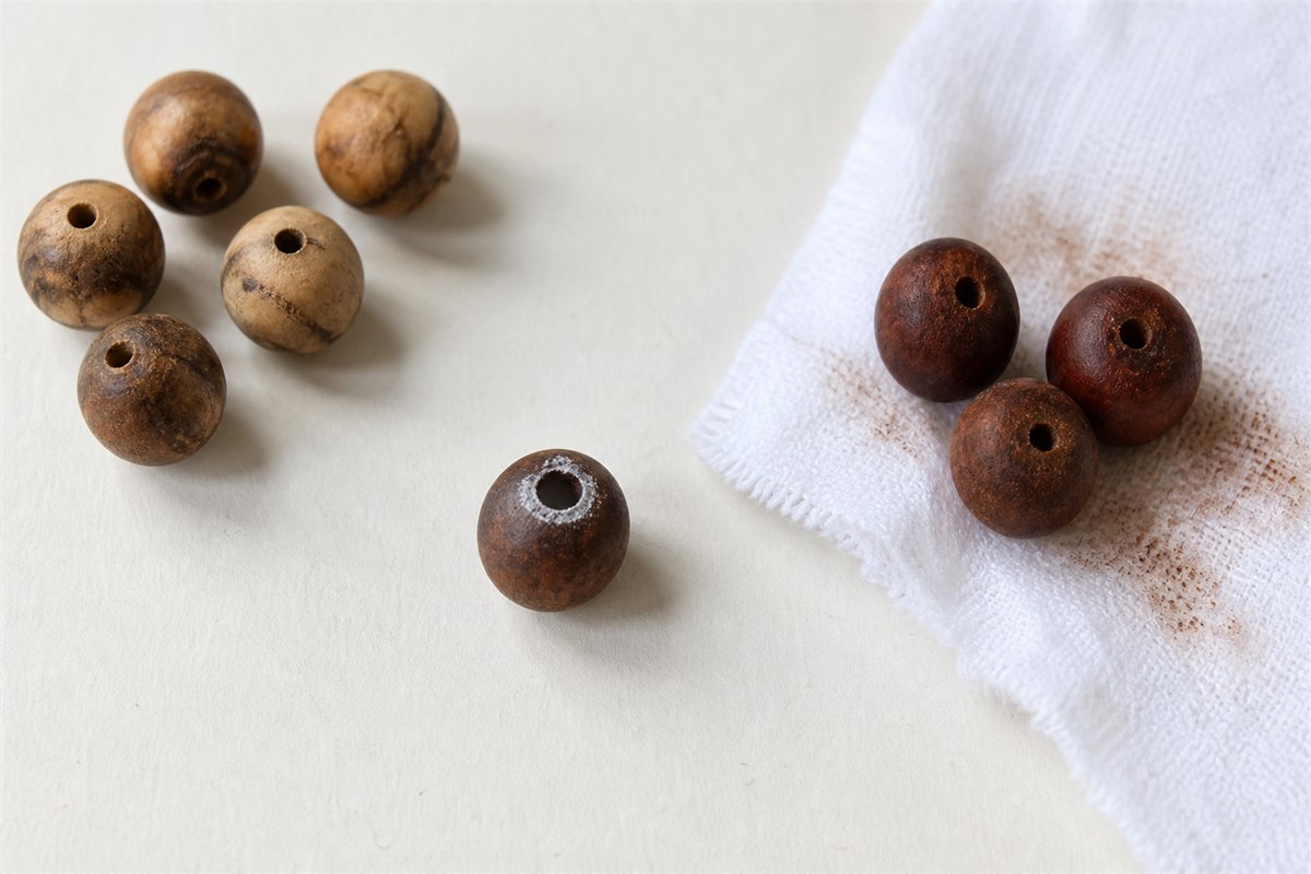 Wooden beads showing grain variation, hole residue, and faint color transfer on cotton