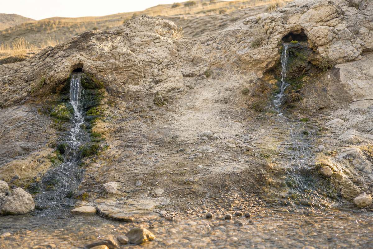 Two separate natural springs flowing from a pale rocky bank