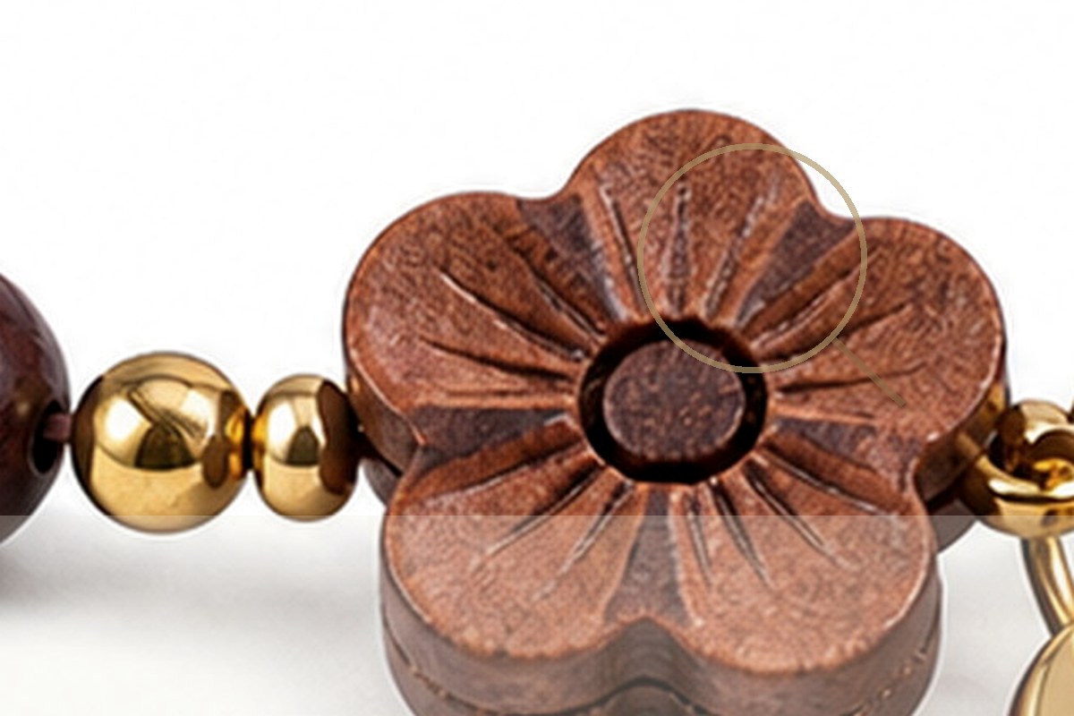 Dark wood bracelet detail arranged with a small magnifying lens on warm paper