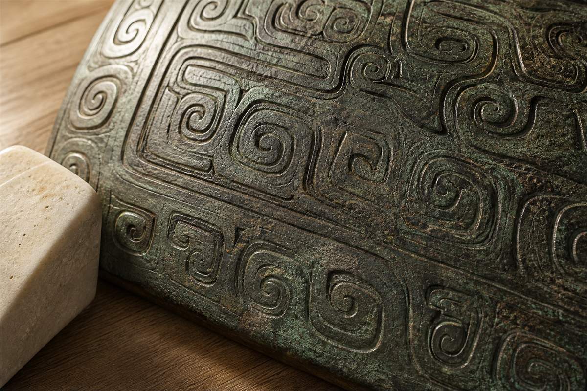 Macro view of repeated rounded and squared spiral lines on a patinated bronze surface