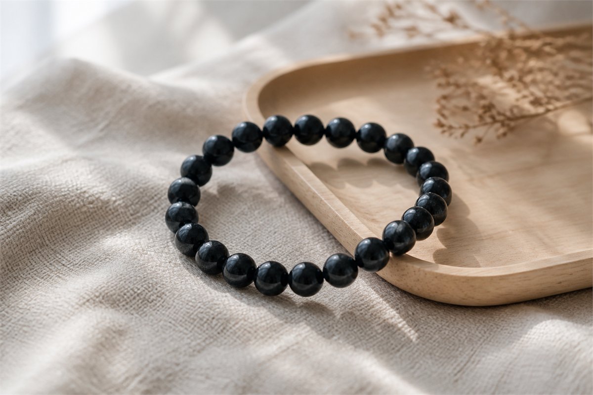Polished black tourmaline bead bracelet on ivory linen and pale wood