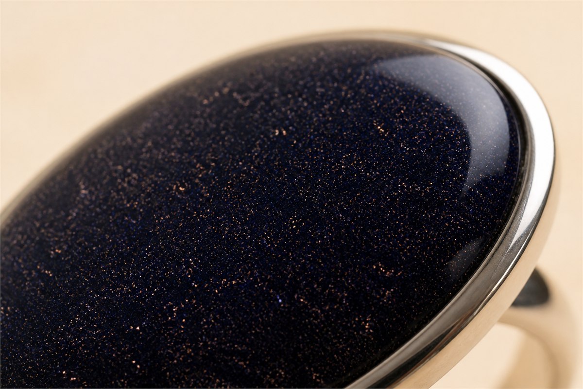 Macro view of deep blue goldstone glass with fine metallic reflections inside a silver bezel