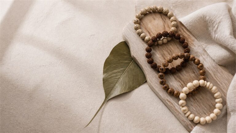 Sacred fig leaf with four distinct Bodhi bead strands on warm ivory linen