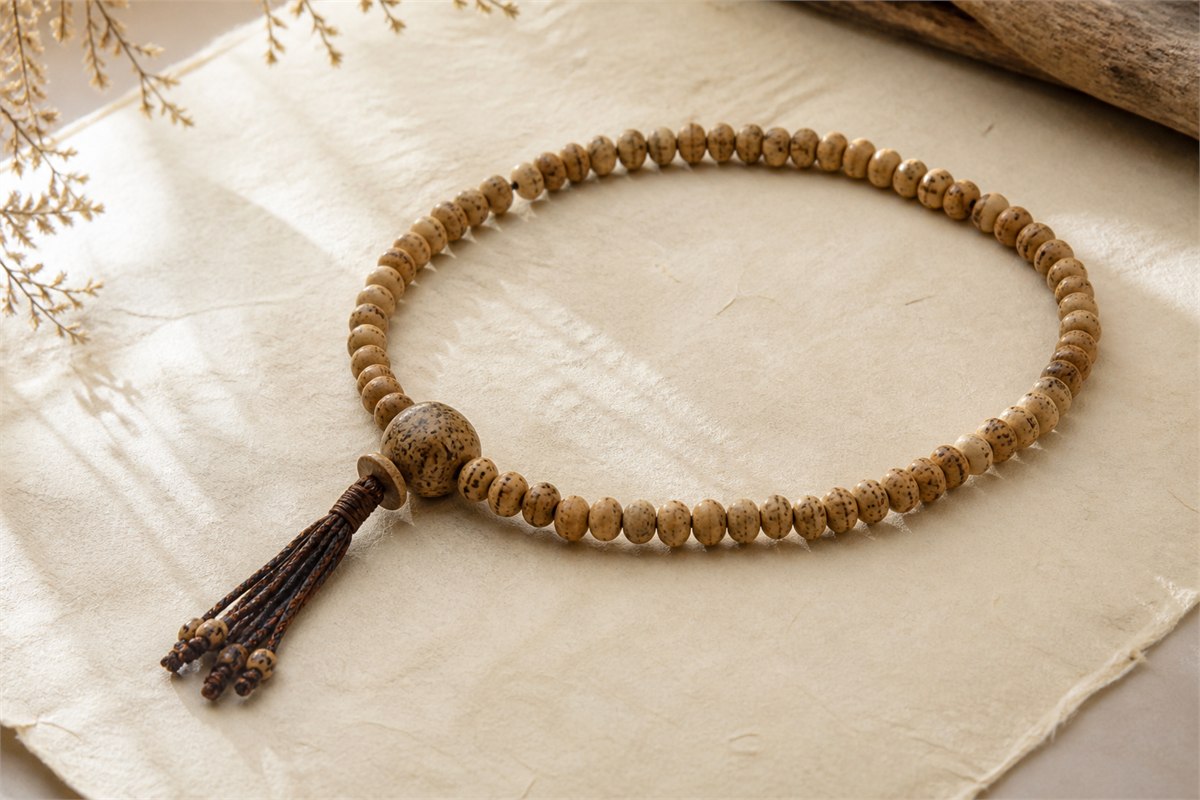 Natural Bodhi seed prayer beads with a larger guru bead and brown tassel on handmade paper