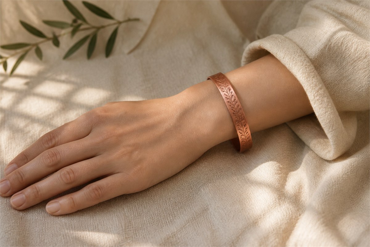 Adult wrist wearing a contemporary chased copper cuff in soft natural light