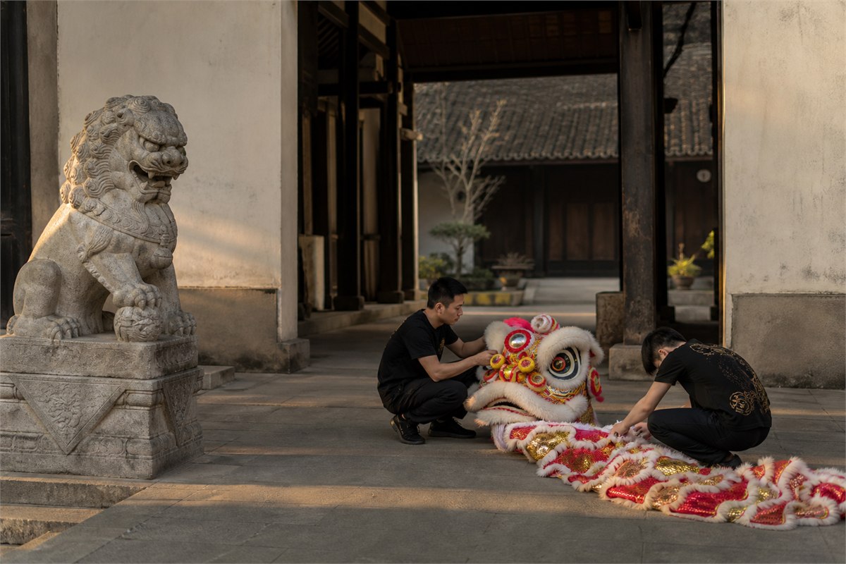Two performers preparing a lion dance costume apart from a stationary stone guardian lion