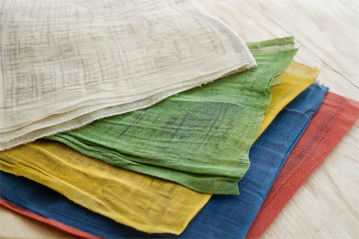 Folded blue, white, red, green and yellow woven cloth seen from the reverse