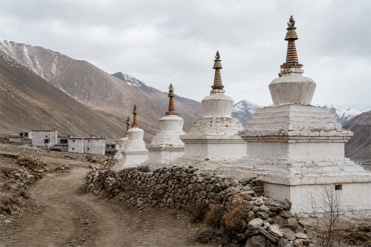 Several white Himalayan chortens with varied proportions along a mountain village path