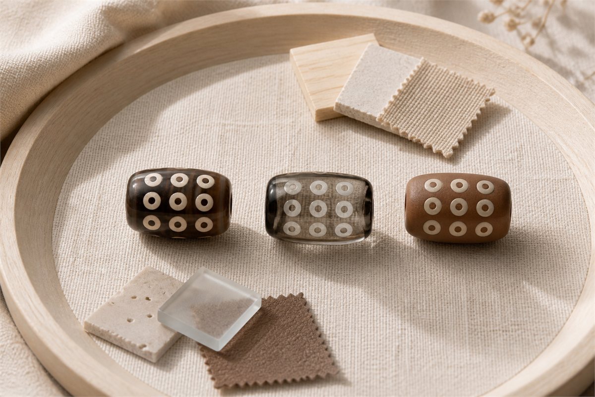 Three modern patterned beads in distinct finishes on a warm neutral tray