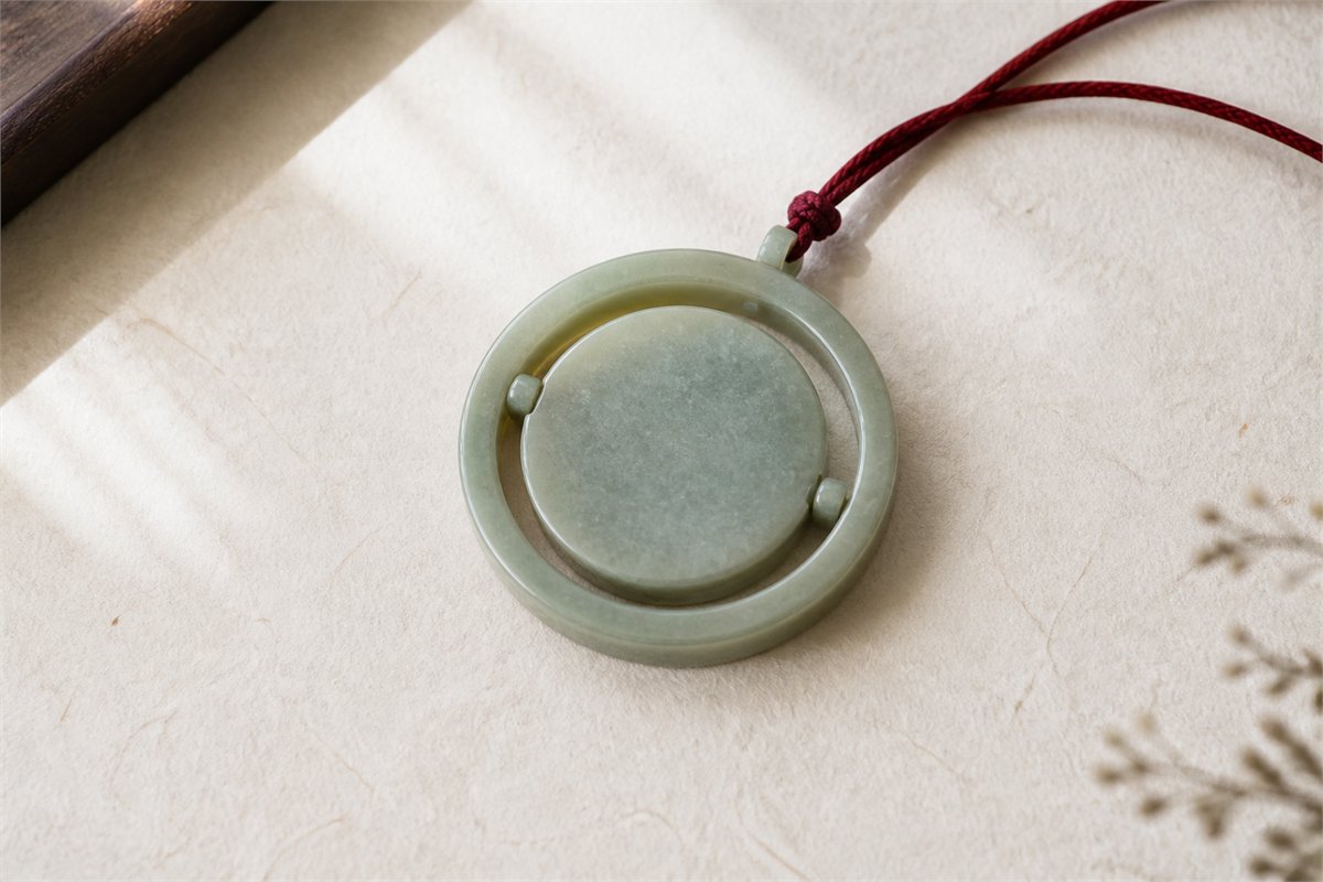 Round pale stone pendant with a movable center held inside an open outer frame