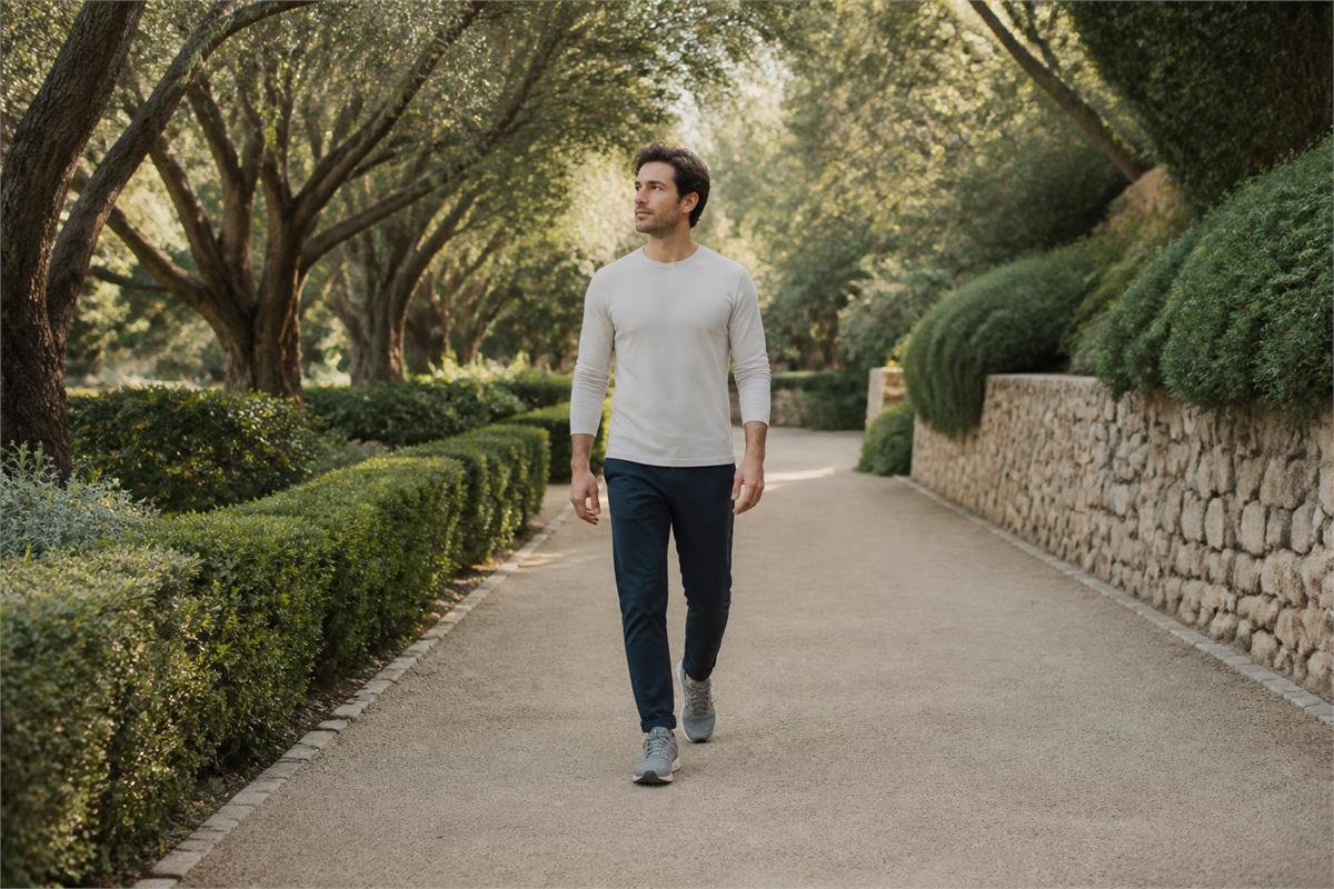 Man walking with eyes open on a clear garden path in ankle-length trousers and stable shoes