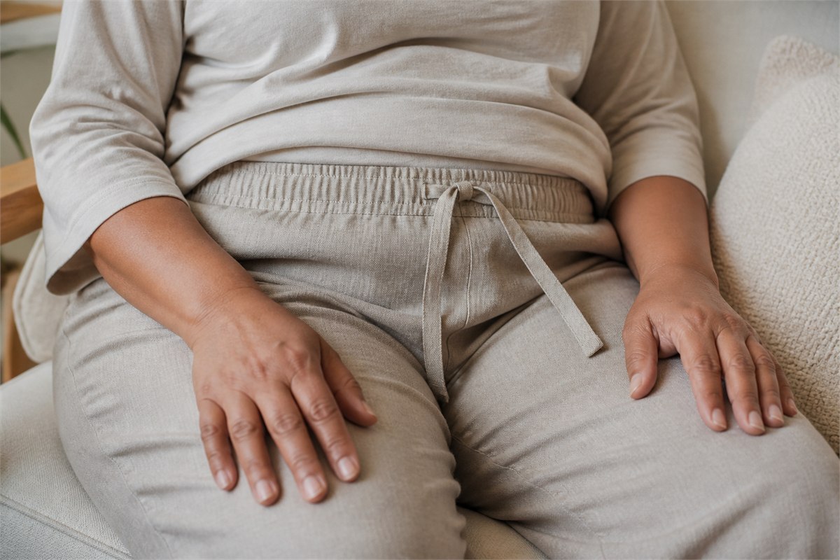 Hands adjusting a broad soft waistband with a flat drawstring on relaxed trousers