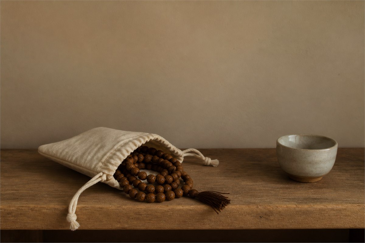 Bodhi seed mala partly stored inside a breathable cream cotton pouch on a wooden shelf