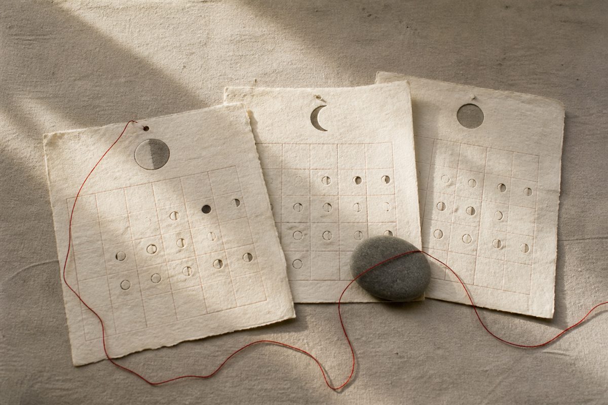 Blank layered calendar pages with moon-shaped cutouts and a red thread