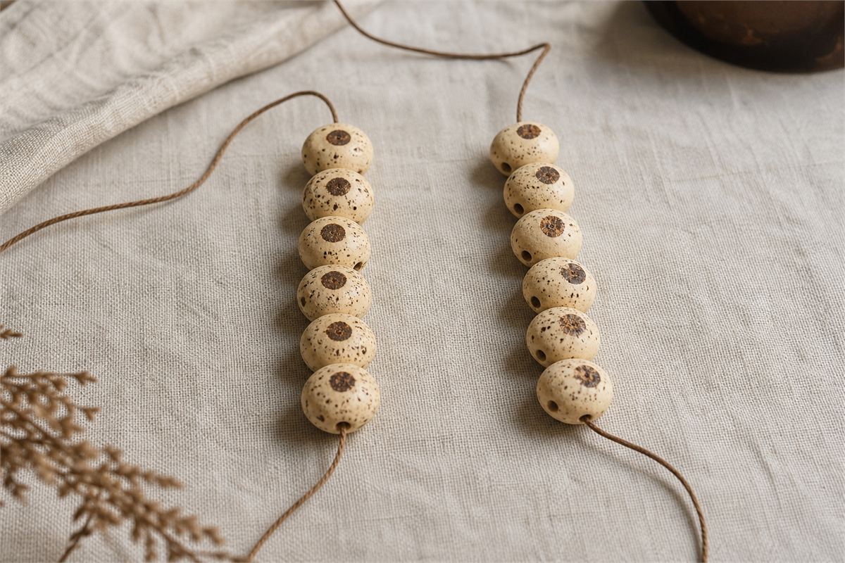 Two rows of cream Xingyue beads showing varied moon-eye placement on linen