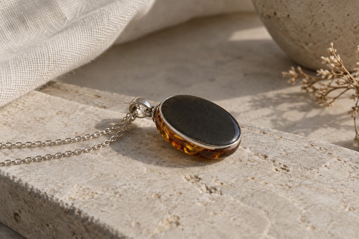 Dark backing and slim silver-colored rim of an amber pendant seen from the side.
