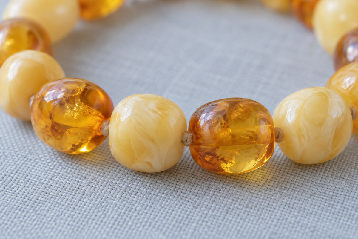 Translucent honey and cloudy cream beads meet along a curved strand.