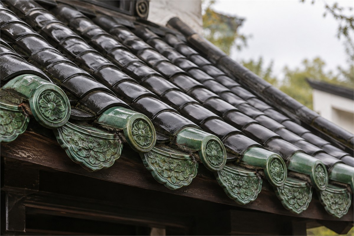 Black curved roof tiles meeting green glazed decorative eave tiles.