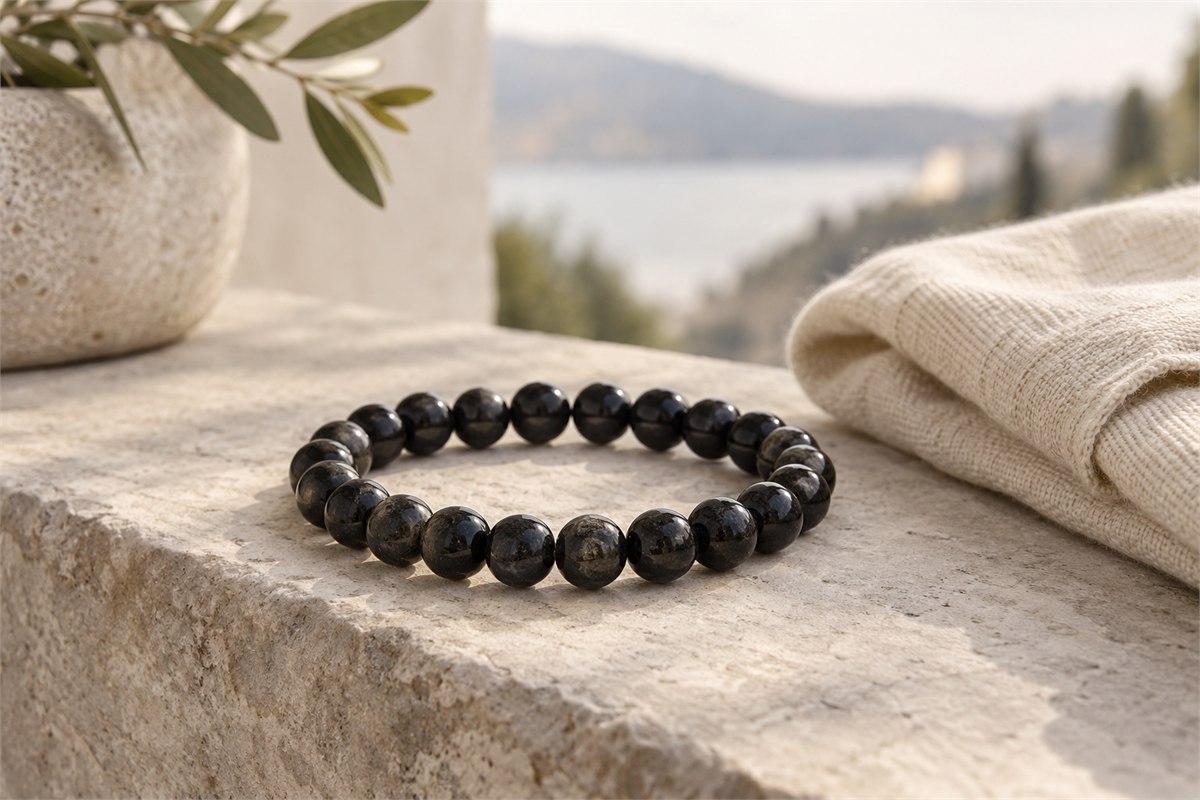 A medium-bead black tourmaline bracelet resting beside a neutral cotton cuff.
