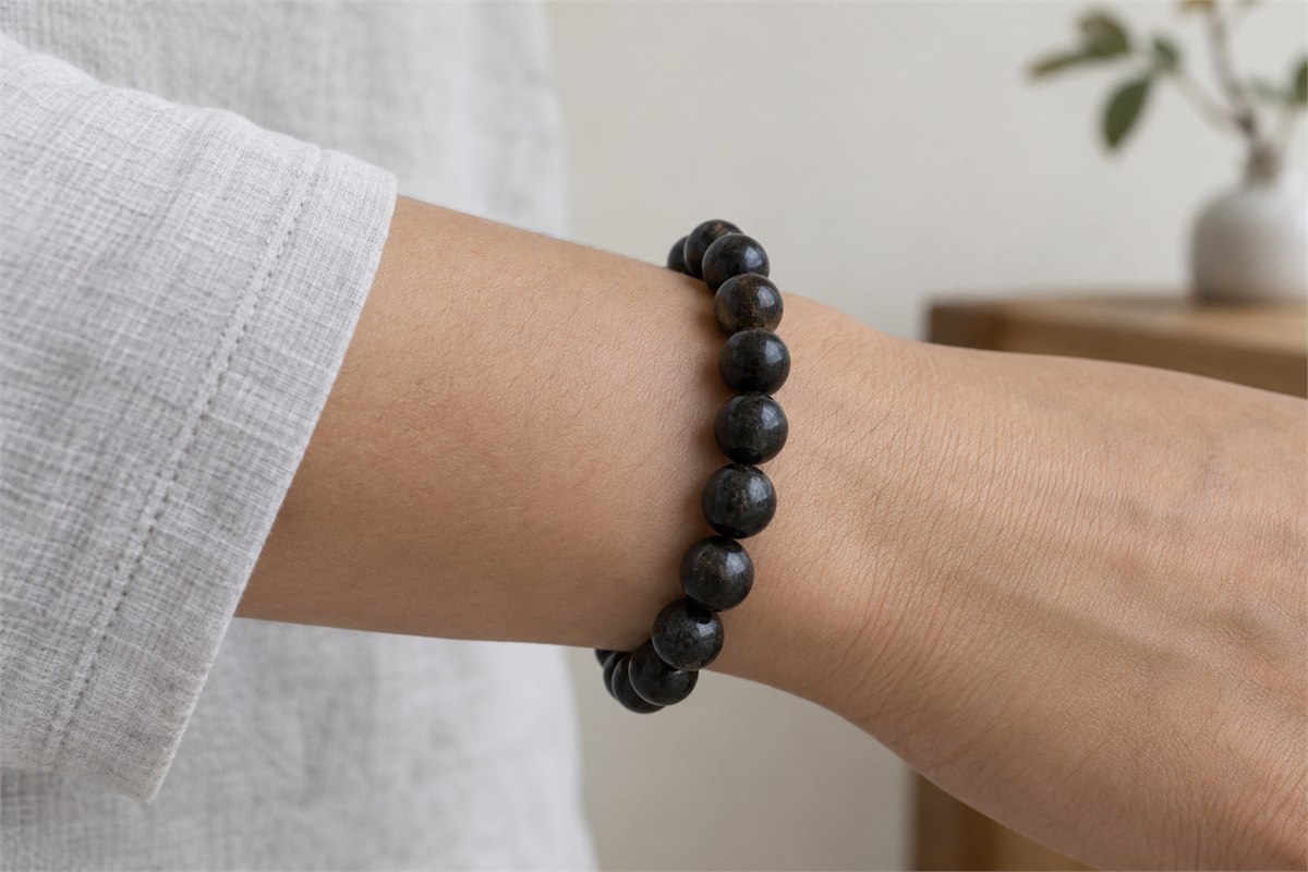 A larger-bead black tourmaline bracelet seen from the side of a relaxed wrist.