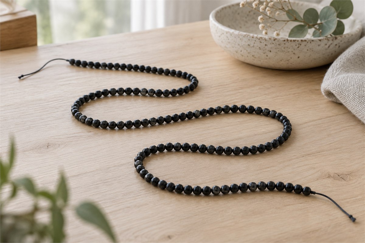 A long strand of small opaque black tourmaline beads in broad loose folds.
