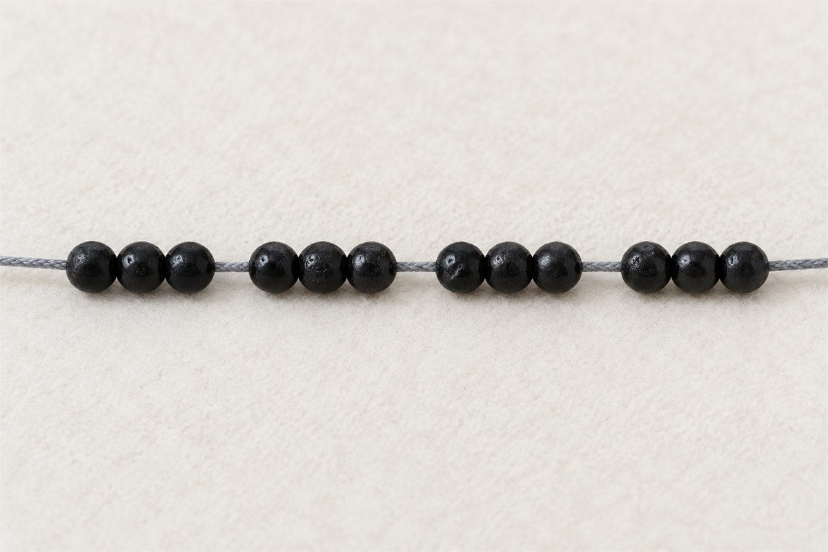 A short open section of small black tourmaline beads on visible cord.