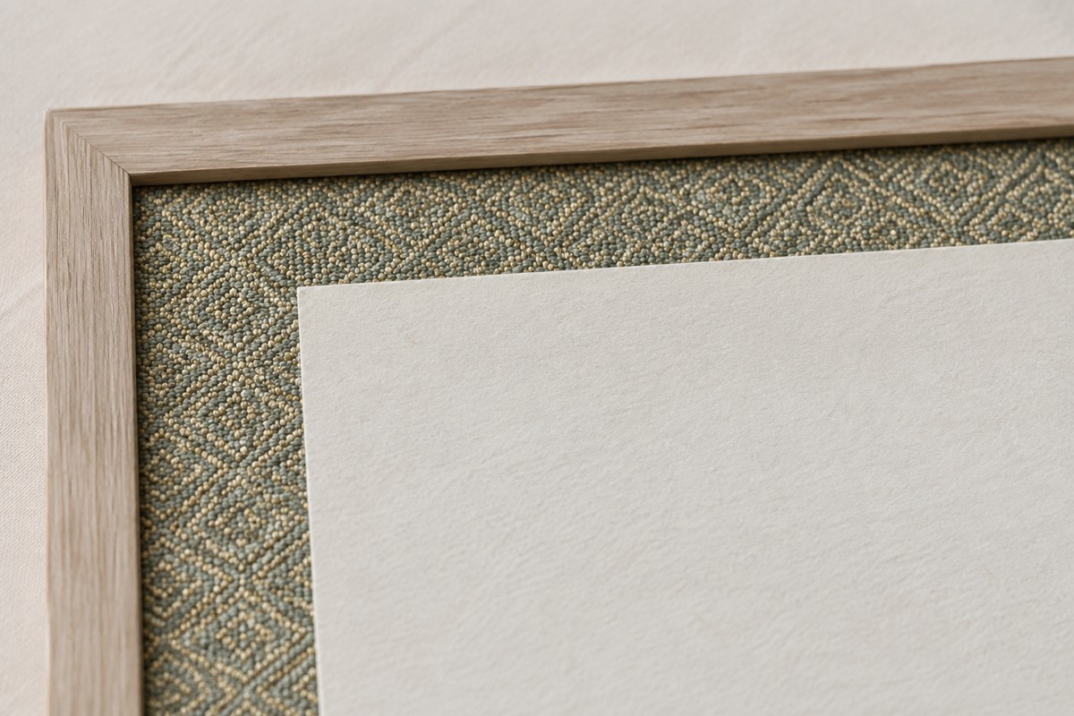 An understated patterned textile border meets a narrow wood frame.